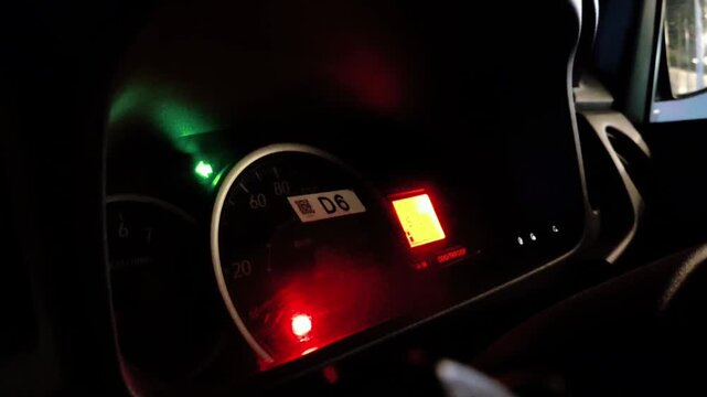 Close up of car dashboard instrument panel at night with flashing turn signal and warning lights.