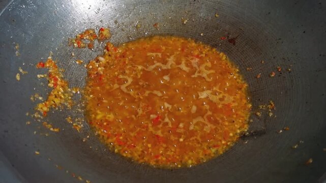 Spicy red chili sauce or sambal base simmering and bubbling in a hot frying wok.
