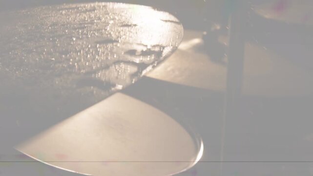 Near cymbal vibrating from backlight flare, droplets shifting, banding showing texture for music