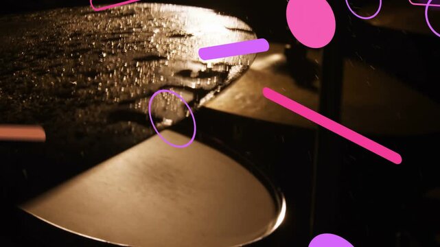 Two metallic cymbals on stands catching warm backlight, water droplets shifting, graphics drifting