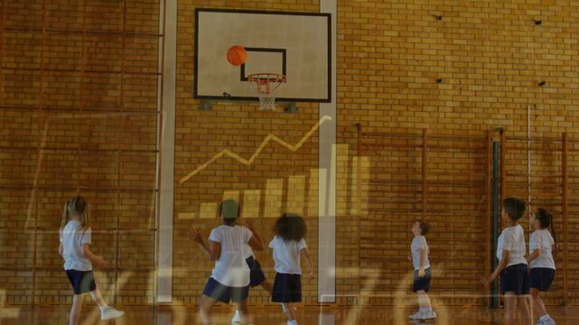 Vertical video: Stepping child shooting orange basketball to score at school in PE kit, overlays