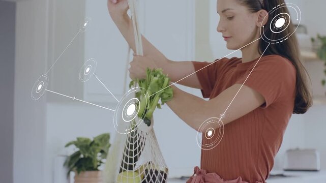 Woman entering kitchen sorting groceries while checking phone, causing home tech HUD mapping items