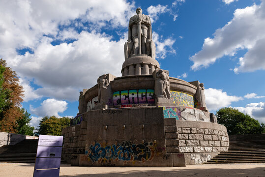 HAMBURG, GERMANY - SEPTEMBER 5, 2025: The monumental Bismarck Monument in Alter Elbpark, covered in modern graffiti including the word PEACE, under a blue sky with white clouds