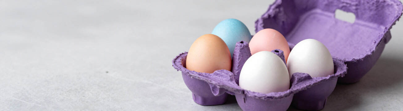 colorful eggs falling onto vibrant purple easter carton placed textured background subtle shadows