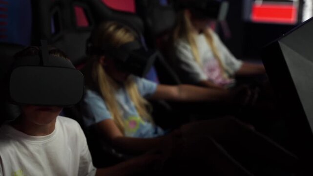 Children wear VR headsets, immersed in games. They sit in darkened booths, focused and engaged. Gaming experience blends technology with playful concentration. Perfect for tech, entertainment