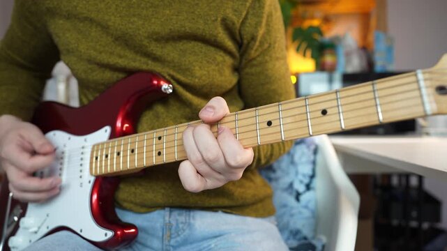 A man playing a red double cut electric guitar. Close up