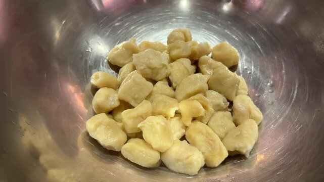 Freshly cooked potato gnocchi being placed in a bowl