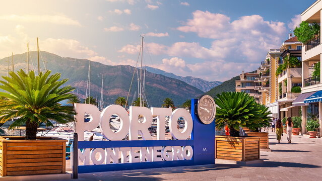 Tivat. Montenegro - August 13, 2023: Porto Montenegro luxury marina village entrance featuring the iconic sign, promenade, palm trees, and Mediterranean architecture.