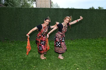 Wandcirkels Dansschool Two female dancers in colorful costumes pose and dance in a park on a summer day  © Шамиль Алиев