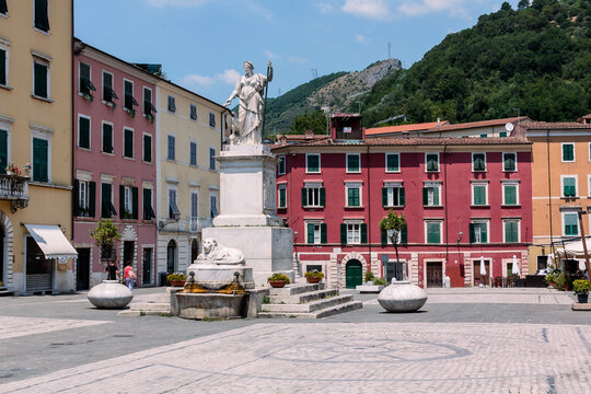 Piazza Alberica in Carrara features a central marble statue (Duchess Maria Beatrice d&rsquo;Este, confirmed) surrounded by elegant pastel buildings with green shutters. The square reflects Carrara&rsquo;s identit