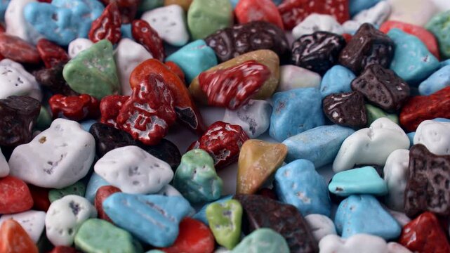 Multicolored stone candies with chocolate falling down close up