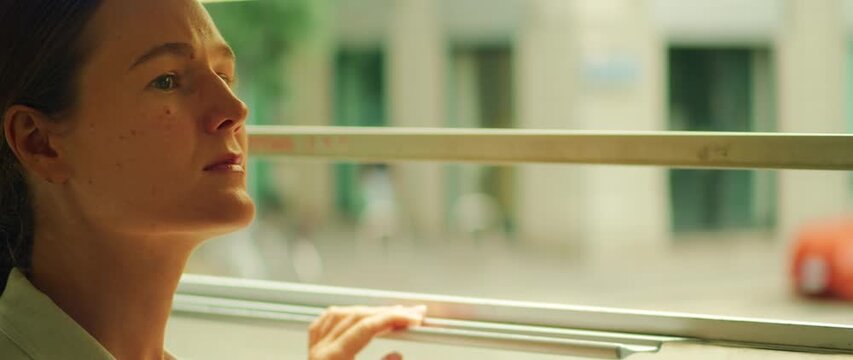 Passenger looking out tram window while traveling through Milan city in summer