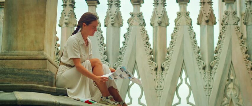 Woman on tourist tour in Milan reading a city map on rooftop of Duomo Cathedral