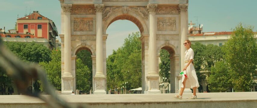 Woman walking by Arco della Pace on a sunny day in Milan city summer Italy