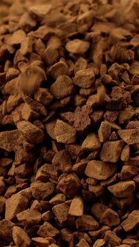 Brown instant freeze-dried coffee grains falling down close up, vertical video