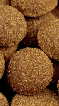 Brown kibble pieces of dry dog food circle rotation close up, vertical video