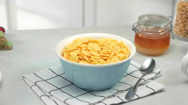 Healthy breakfast cereal, corn flakes, bowl with milk, honey, nuts and fruits on kitchen table