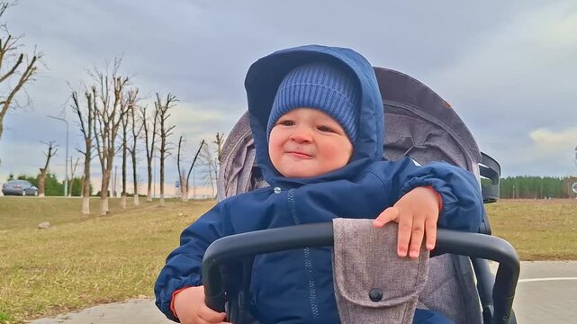Cute baby boy smiling and playing with soap bubbles in a stroller