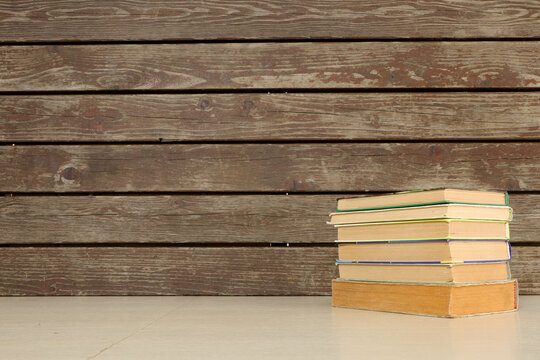 Vintage books stack on wooden background with copy space on the left