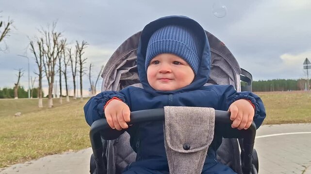 Happy little boy smiling in a stroller during autumn walk