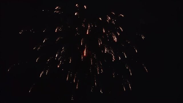 Bright burst against dark night sky, with rising smoke trails