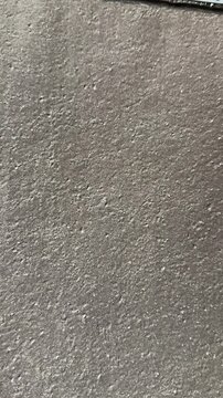Close-up rolled roofing texture vertical granules, asphalt membrane with coarse grit and parallel ridges, neutral gray tones, macro.