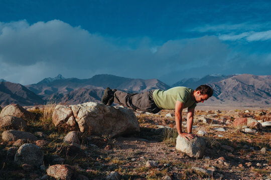 Man doing elevated push ups outdoors using rocks