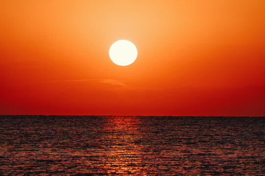 Close view of bright sun above lake horizon at sunset