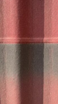 Red gray corrugated ondulin tile closeup showing textured waves, sunlight casting striped shadows, visible fastener detail.