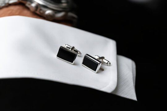 Elegant rectangular black onyx cufflinks with silver trim resting on a crisp white shirt cuff, luxury accessory