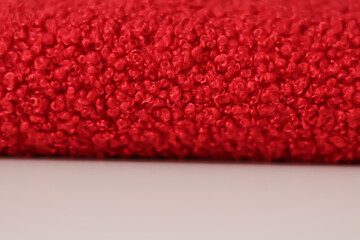Red teddy fleece fabric on white table with copy space for text and blurred foreground © LadyLensArt 