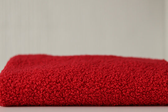 Close up of a vibrant red soft teddy bear fabric with a shallow depth of field. Professional textile background with bokeh for fashion design sewing and winter clothing marketing concepts. 