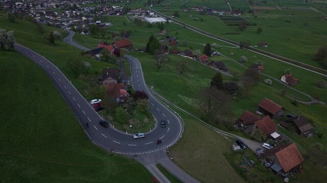 Aerial static drone shot capturing a mountain hairpin curve with cars climbing and motorcycles descending, showing dynamic alpine road traffic and elevation changes.