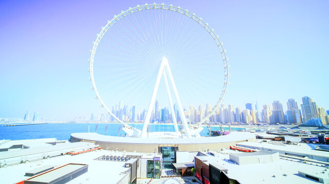 conic giant observation wheel by the waterfront with a modern skyline backdrop