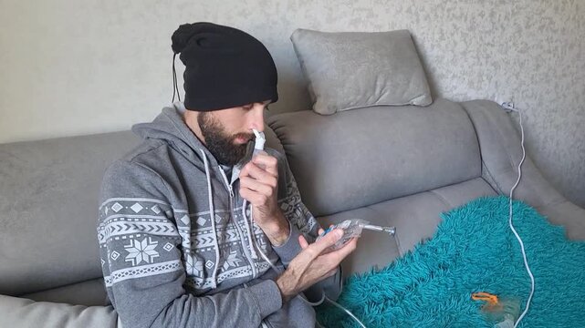 Portrait of a Caucasian man using a compressor nebulizer for flu relief, medical home care, healthy lifestyle, treatment.