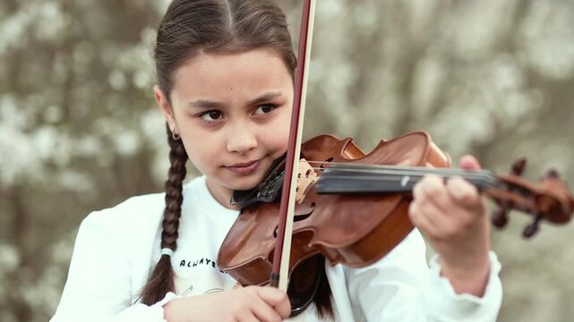 Little Girl Playing Violin in Sunny Summer Park, 4K 10-bit Cinematic Footage.