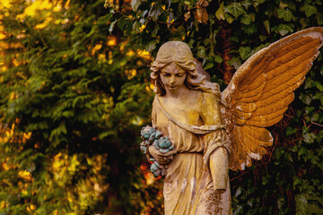 Fototapeta premium Weathered angel sculpture with damaged wing, concept of grief, memory and mortality.