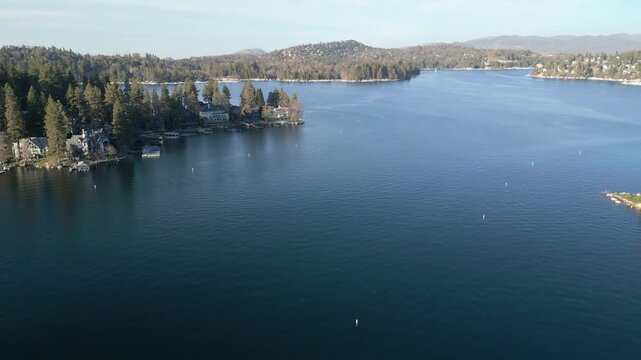 Aerial drone footage of Lake Arrowhead shoreline with waterfront homes, docks and forest. Smooth aerial video of a calm mountain lake with lakeside houses, docks and pine forest in Lake Arrowhead