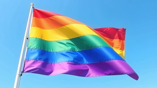 LGBT rainbow flag waving in the sky against blue clouds, pride symbol, diversity and equality, social movement.