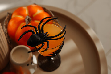 Fototapeta premium Halloween drink with a spider decoration and pumpkins on a tray in a cozy setting