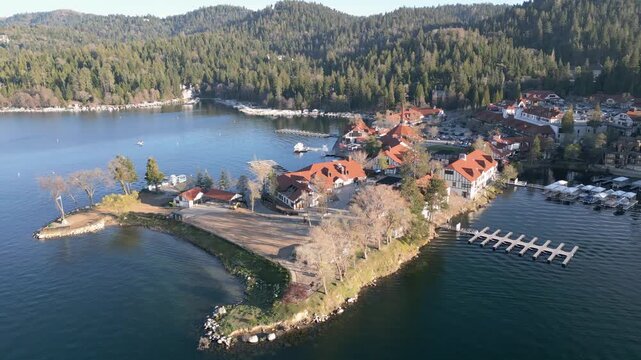 Aerial drone footage of Lake Arrowhead Village marina with docks, waterfront buildings and forest. Aerial video of Lake Arrowhead Village showing marina docks, waterfront buildings and surrounding pin