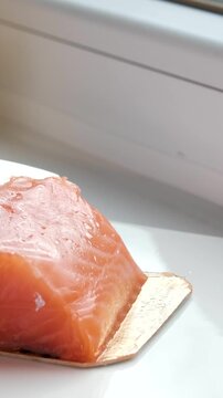 Chef slicing fresh salmon fillet with precision on a cutting board in a professional kitchen. Close-up of hands in black gloves and raw fish texture. High quality 4k footage