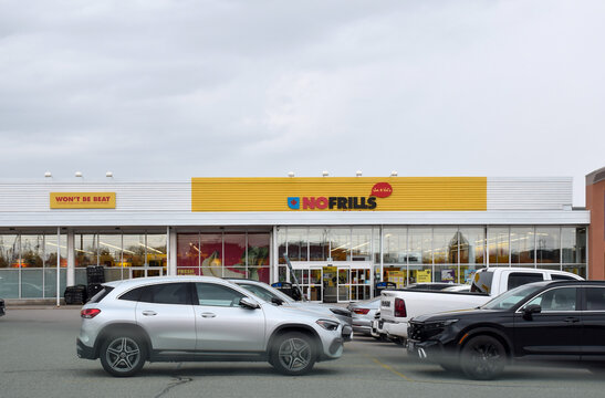 No Frills grocery store entrance viewed from plaza parking lot. Retail storefront with signage in commercial shopping area. Aurora, Ontario, Canada, April 2026