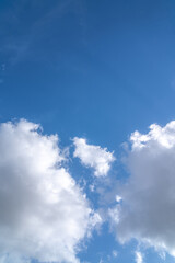 Obraz premium Blue sky with white fluffy clouds, vertical cloudscape background with copy space for text overlay