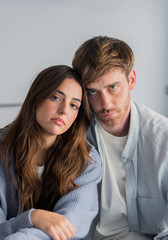 Obraz premium Thoughtful young couple sitting close together looking serious and contemplative in a home portrait