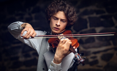 Young male violinist playing violin in elegant attire © Maestro7