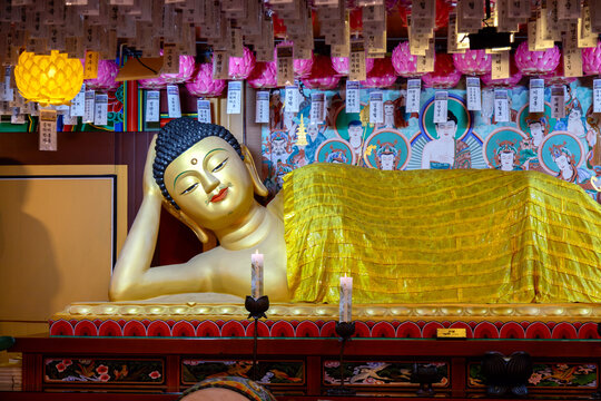 Close-up of a golden reclining Buddha statue with serene facial expression inside a Korean Buddhist Haedong Yonggungsa temple in Busan, South Korea