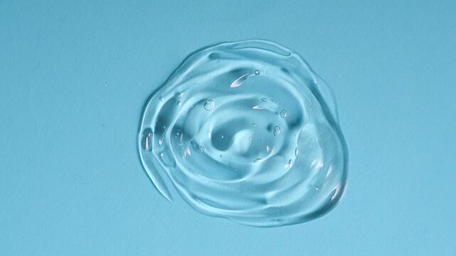 Transparent gel drop. Liquid cream gel cosmetic smudge texture on blue background. Cosmetics serum gel, hyaluronic acid cream background, facial treatment 