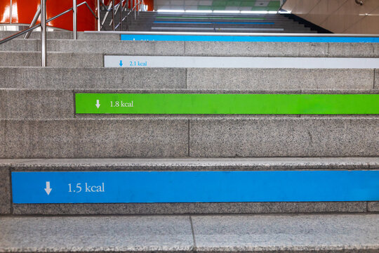 Granite stairs in a Korean subway station with colorful blue and green calorie counter stickers on each step, showing kcal burned per step as a public health initiative