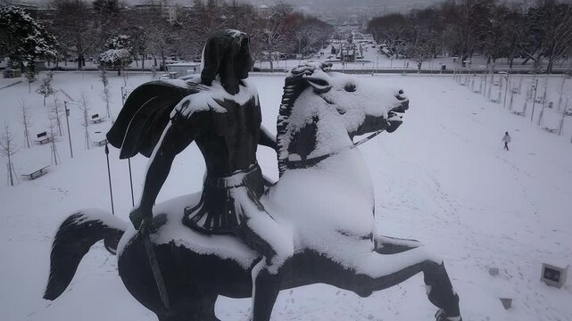 Aerial circling shot of the Alexander the Great monument covered in snow. Winter view of the famous bronze statue at the waterfront of Thessaloniki, Greece.